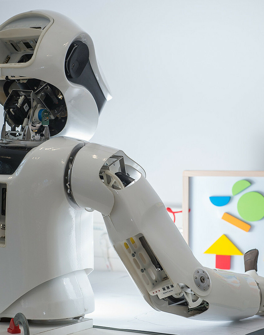 Humanoider Roboter vor einer Tafel mit geometrischen Elementen
